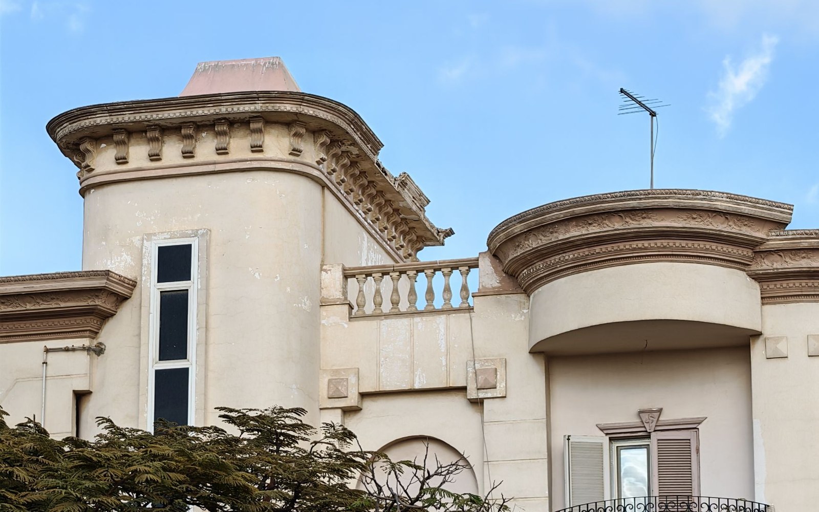 Ornate cornice and rounded turret detail on an old stucco building facade